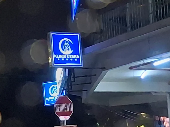 Illuminated Klinik Utara signage at night